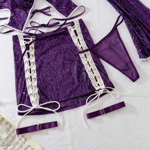 Flat lay of purple sequin party set with mini skirt, sleeves and decorative satin straps