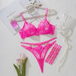 Vue à plat d'un ensemble de lingerie en dentelle rose avec soutien-gorge et jarretières