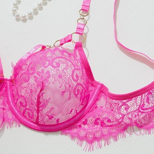 Détail d'un soutien-gorge en dentelle rose avec motifs floraux et anneaux en métal doré