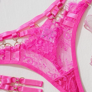 Détail de sous-vêtements en dentelle rose avec anneaux dorés et design à lanières ajourées