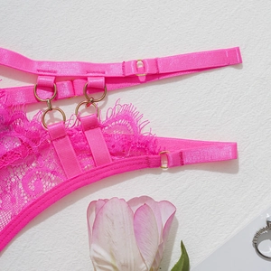 Détail de lingerie en dentelle rose vif avec anneaux dorés et décor floral doux
