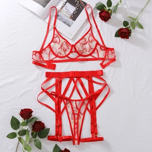 Détail à plat d'une broderie cœur rouge sur ensemble de lingerie en tulle avec roses