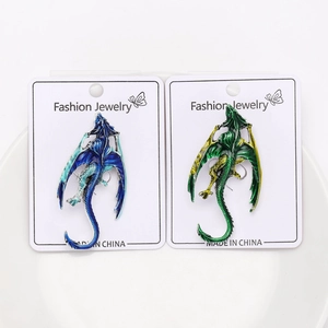 Macro shot of blue and green enamel dragon brooches on display cards in a white bowl