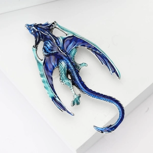 Detailed close-up of dragon brooch with gradient blue enamel on silver metallic base