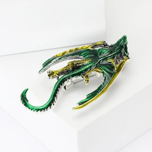 Detailed macro view of an emerald green dragon brooch with yellow enamel on silver metal