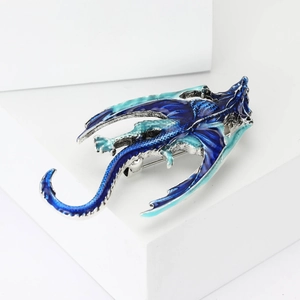 Macro detail of enamel dragon brooch with blue gradient on a white platform