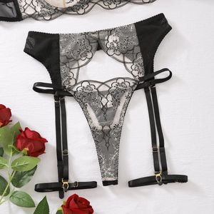 Détail du porte-jarretelles en dentelle noire et du T-back avec broderie florale fine