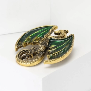 Close-up of golden dragon brooch with green enamel wings and detailed scales