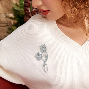Gros plan d'une broche tulipe de luxe en argent avec zircon sur un pull blanc