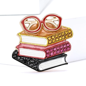 Macro shot of stacked book brooch with colorful rhinestones and red glasses detail