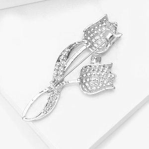 Détail d'une broche tulipe argentée avec cristaux sur un support géométrique blanc pur