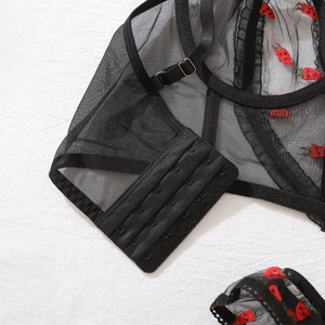 Détail de lingerie en maille noire avec broderie fraise et fermeture à quatre rangées