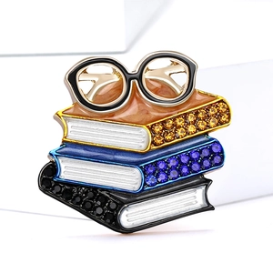 Macro shot of stacking enamel books and glasses brooch with colorful rhinestones details
