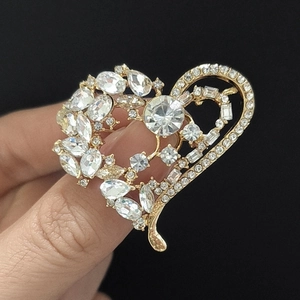 Gros plan d'une broche coeur dorée ajourée avec des cristaux de strass étincelants