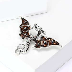 Détail macro d'une broche dragon argentée avec émail marron et cristaux colorés