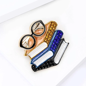 Detailed close-up of colorful enamel book and glasses brooch with sparkling rhinestones