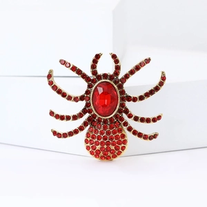 Macro detail of luxury spider brooch with red rhinestones and gold-plated finish