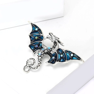 Détail de la broche dragon argenté avec ailes en émail bleu et strass colorés
