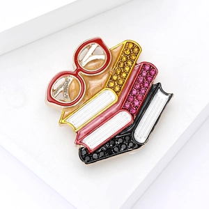 Detail of colorful enamel stacked books and red glasses brooch with sparkling rhinestones