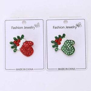 Detailed macro of festive rhinestone Christmas glove brooches with red and green enamel finish