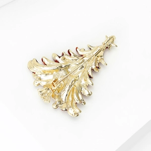 Golden Christmas tree brooch with safety pin back on a clean white background