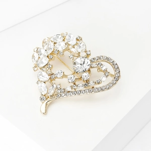 Détail d'une broche en forme de cœur avec strass étincelants sur un support blanc