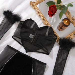 Détail du corset en résille noire avec motif cœur et gants bordés de plumes noires