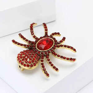 Macro view of detailed spider brooch with red rhinestones on polished gold alloy