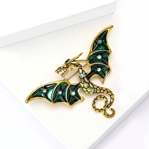Détail de la broche dragon dorée avec ailes en émail vert émeraude et strass