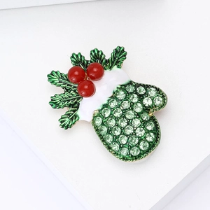 Close-up of Christmas glove brooch with green rhinestones and red berries on white background