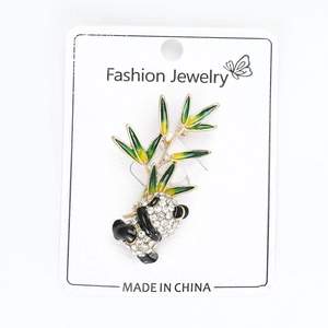 Detail of panda brooch featuring white rhinestones, black enamel and green bamboo leaves