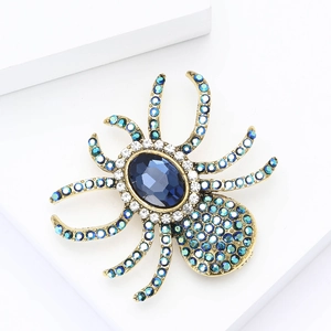 Detailed close-up of a spider brooch with blue gemstones and rhinestones on a stand