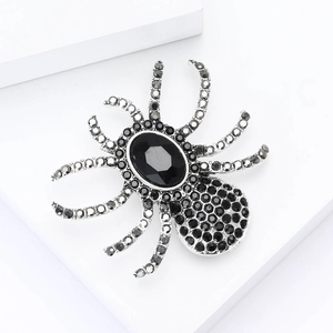 Macro detail of a silver-toned spider brooch featuring black faceted stone and dark rhinestones