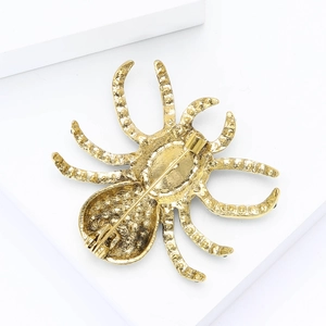 Macro detail of the vintage gold spider brooch showing back pin structure and alloy texture