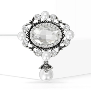Dettaglio macro di spilla vintage con cristallo ovale ed elegante ciondolo in perla
