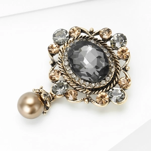 Dettaglio macro di spilla vintage con gemma grigia, strass e ciondolo a perla