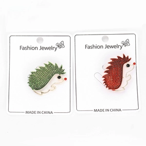 Detail of red and green hedgehog brooches with crystals on gold-toned metal plating