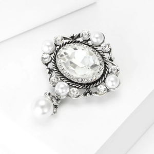 Dettaglio macro della spilla vintage con cristallo ovale, perle e ciondolo elegante