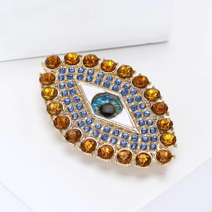 Λεπτομερής λήψη macro από καρφίτσα Evil Eye με μπλε κρύσταλλα και χρυσή μεταλλική βάση
