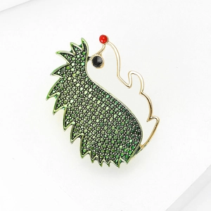 Detailed close-up of hedgehog brooch with green rhinestones and golden metal alloy texture