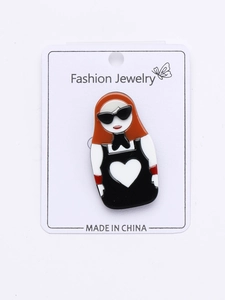 Detailed close-up of fashion girl acrylic pin with orange hair and sunglasses on white card