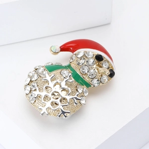 Funkelnde Strass-Weihnachtsschneemann-Brosche mit rotem Emaille-Hut auf weißem Podest