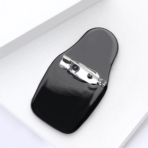 Detailed view of the black acrylic brooch back with a silver safety pin clasp on a white stand