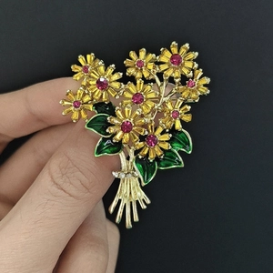 Detailed macro of a gold flower bouquet brooch with pink crystals and green enamel leaves