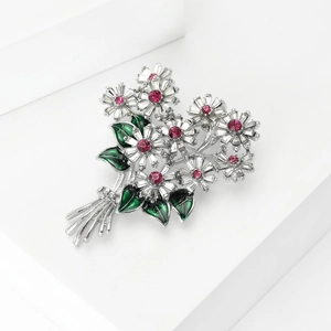 Exquisite flower bouquet brooch with red crystal and green enamel on a white background