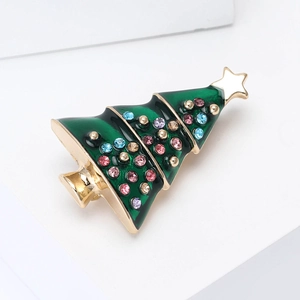 Close-up of golden Christmas tree brooch with green enamel and colorful rhinestones