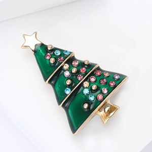 Detailed macro view of enamel Christmas tree brooch with colorful rhinestones on white base