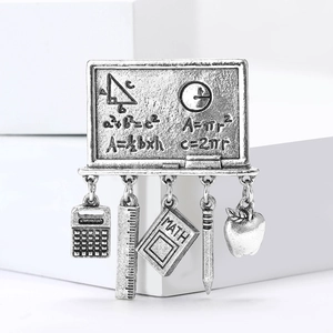Detail of vintage silver math brooch with blackboard and education themed charms