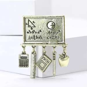 Macro detail of math-themed chalkboard brooch with vintage gold finish and school charms
