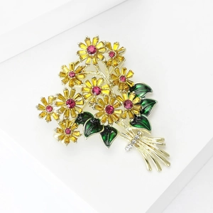 Detail of yellow crystal daisy bouquet brooch with green enamel leaves and golden ribbon